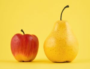 Ein roter Apfel und eine gelbe Birne stehen vor gelbem Hintergrund.