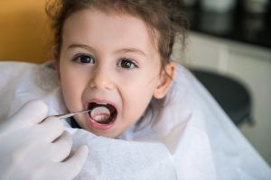 Zahnarzt untersucht Kind auf Kreidezaehne