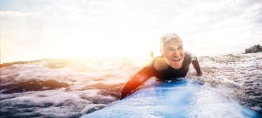 Ein Rentner surft auf dem Meer.