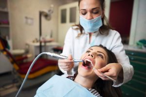 Zahnärztin reinigt die Zähne einer Patientin.