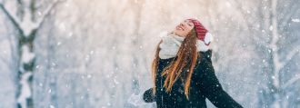 Junge Frau mit langen Haaren in Winterkleidung genießt den Schnee.